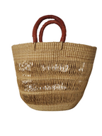 A brown natural basket with a sturdy handle, made from elephant grass for the beach 